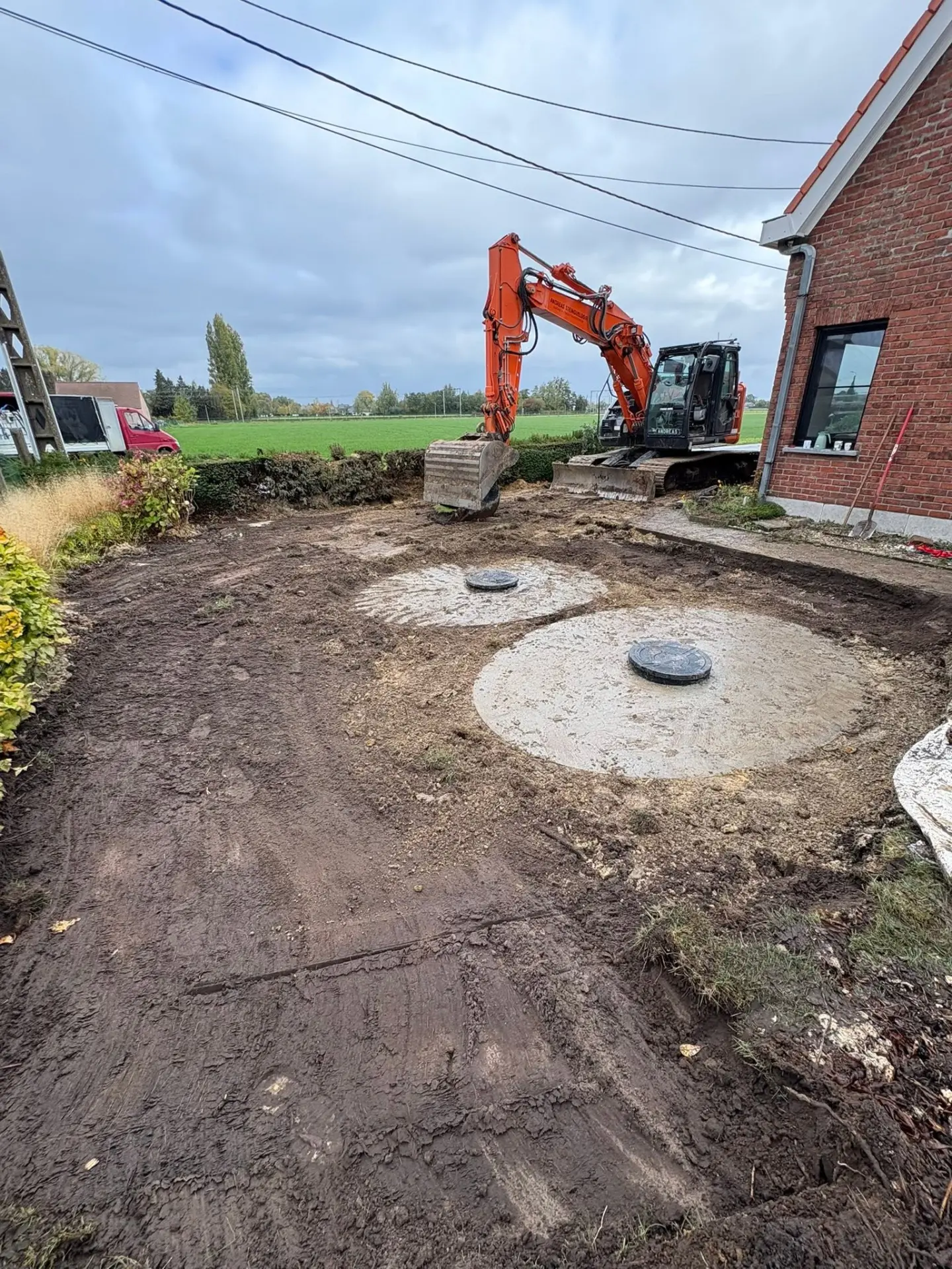 Graafmachine op een werf met afgewerkte betonnen putten